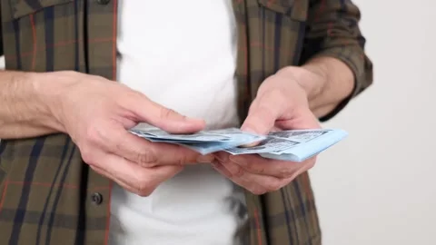 A close-up captures men's hands carefully counting a stack of dollar banknotes 動画素材 307416941