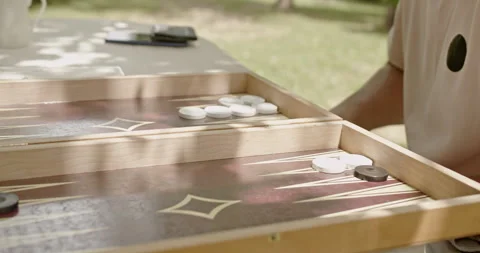 Close-up capturing a person playing backgammon on a wooden board outdoors 스톡 동영상 283315946