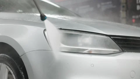 Close-up of a car being washed with high-pressure water, focusing on the front Video stock 287229063