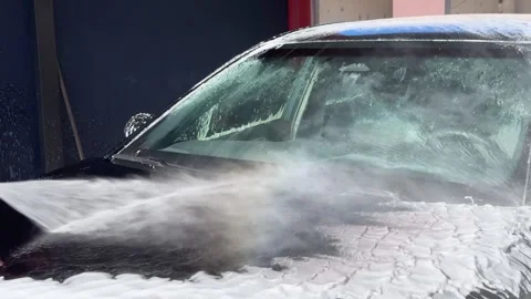 Close-up of a car being washed with a high-pressure water sprayer at a self Stock Footage 313265562