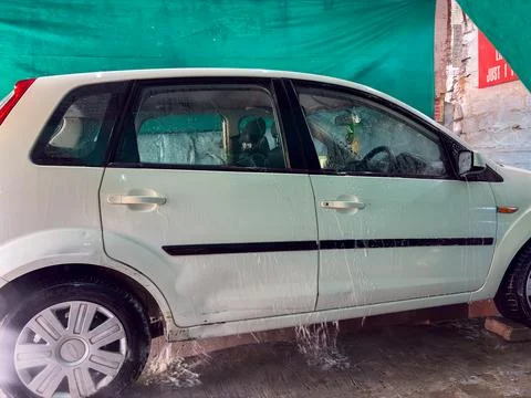 Close up of car cleaning process with water spray on vehicle tire Stock Photos