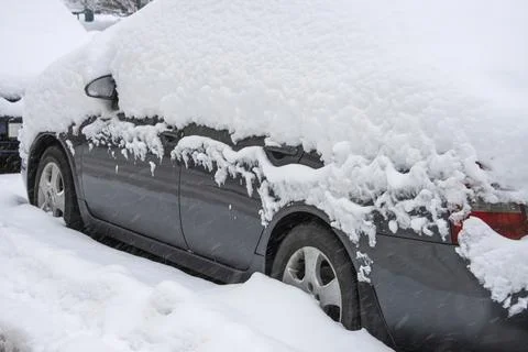 Close-up of a car covered in a thick layer of snow during a snowstorm Stock Photos