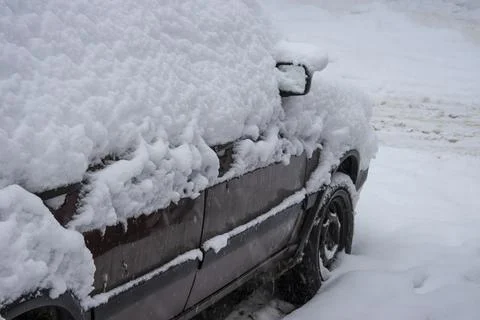 Close-up of a car covered in a thick layer of snow during a snowstorm Stock Photos