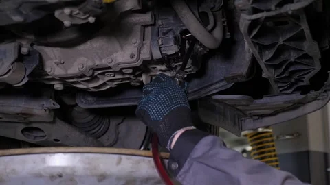 A close-up of the car drains excess engine oil in the car at the service station Stock Footage 297839064