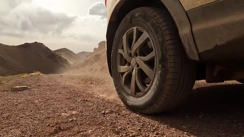 Close-up of a car driving on a dirt rocky road, creating dust Video stock 241381053