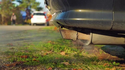 Close-up of a car exhaust pipe letting out gases, with visible rust on muffler Stock Footage 295093231