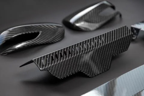 A close-up on a car exterior elements made from carbon fiber of interwoven bl Stock Photos