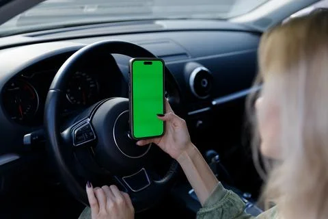 A Close-Up in a Car Interior Featuring a Hand Holding a Smartphone with a Green Stock Photos
