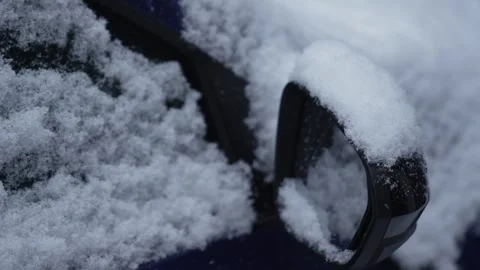 A close-up of a car mirror covered in snow on a snowy winter day. Snowfall. Stock Footage 325367260