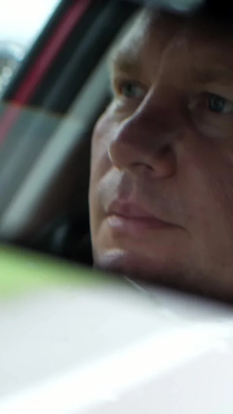 Close-up, in the car rear-view mirror the driver's face is visible, he seriously Stock Footage 314564482