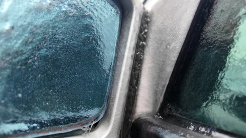 Close up of a car side mirror covered in ice and dripping meltwater Vídeos de archivo 329402883