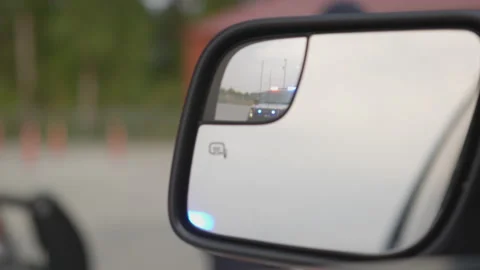 Close up of Car Side Mirror Reflecting Police Cruiser with Flashing Lights Stock Footage 219543670