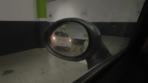 Close-up of a car side mirror reflecting a parking garage and another car, Cote Stock Footage 344827369
