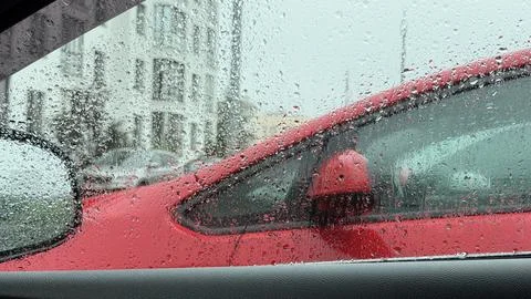 Close-up of a car window heavily dotted with raindrops, partially obscuring the Stock Photos