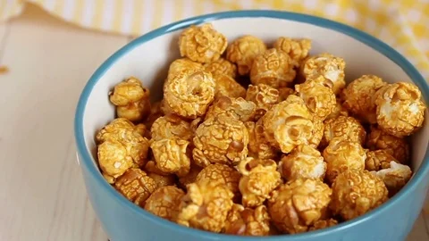 Close up of caramel popcorn pours into bowl on wooden table Stock Footage