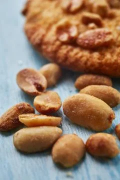 Close-up of caramelized roasted peanuts on blue wooden background Stock Photos