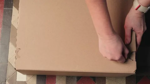 A close up of a cardboard box and the hands of a person carefully removing the Stock Footage 330610127
