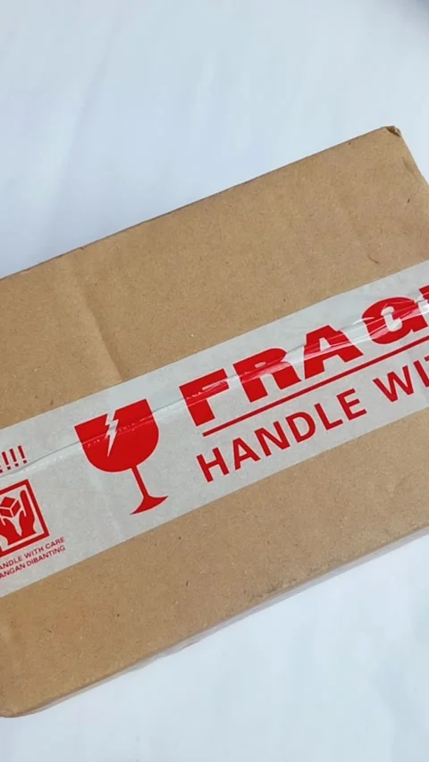 Close up of a cardboard package ready to be opened. Thumb rubbing the adhes.. Vídeos de archivo 330749256