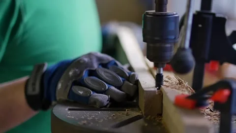 Close-up. a carpenter drills a walnut board with a milling cutter for wood, Man Stock Footage 152348099