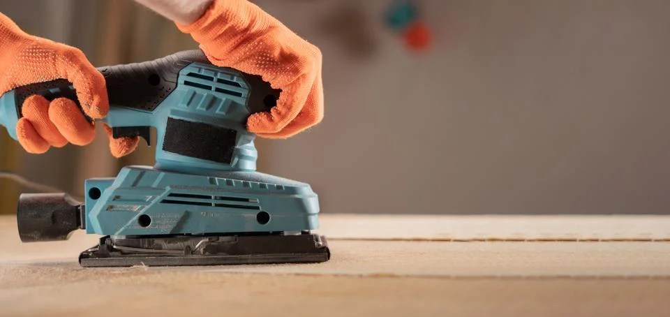Close-up of carpenter hands with sander at workshop for polish. wood worker u Stock Photos