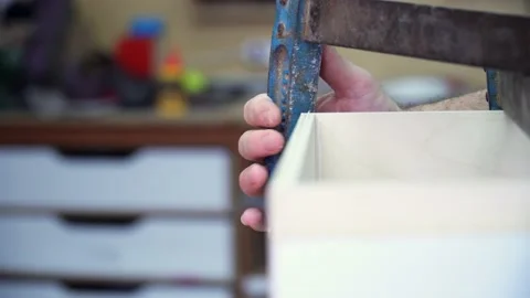 Close up on carpenter hands using metal vise tools to assemble a wooden Stock Footage 220759078