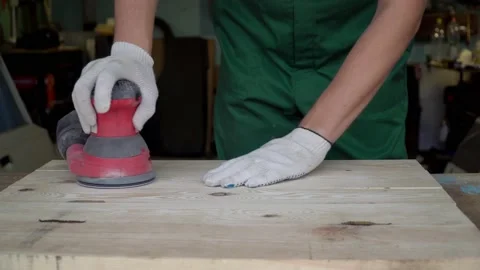 Close up carpenter at home workshop polishes wooden board with a electric orbita Stock Footage 229734276