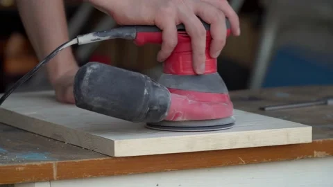 Close up carpenter at home workshop polishes wooden board with a electric orbita Stock Footage 230291855