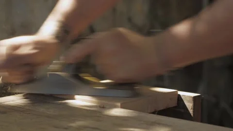 Close up of a carpenter planing a plank of wood with a hand plane. Hands of a Stock Footage 139446491