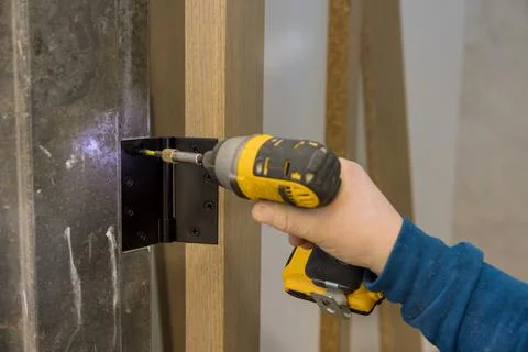 Close-up carpenter process of hands screwing hinge on a door with screwdriver Stock Photos