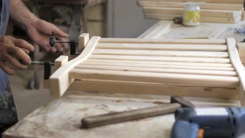 Close-up of a carpenter tightening two screw clamps to a piece of light wood.A Stock Footage 201053530