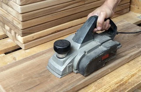Close-up of a carpenter using an electric planer on a wooden board Stock Photos
