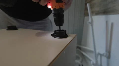 A close-up of a carpenter using a power screwdriver to assemble a new piece of Stock Footage 320963960