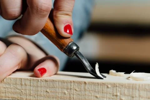 Close-up carpenter woman's hand with a red manicure treats the tree, cuts the Stock Photos