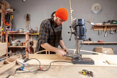 Close up of carpenter in work clothes carving a wooden on an drill. Manual jo Stock Photos