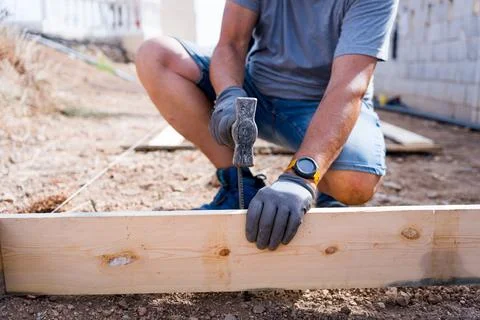 Close up of a carpenter worker hands using hammer to drive a nail into a wooden Stock Photos