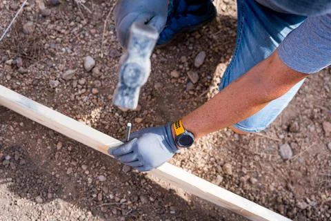 Close up of a carpenter worker hands using hammer to drive a nail into a wooden Stock Photos