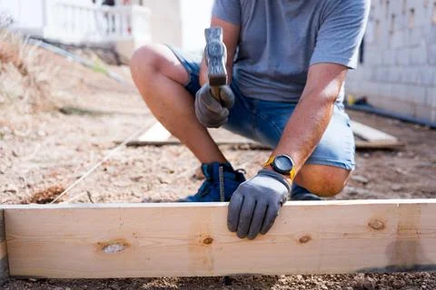 Close up of a carpenter worker hands using hammer to drive a nail into a wooden Stock Photos