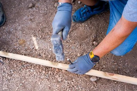 Close up of a carpenter worker hands using hammer to drive a nail into a wooden Stock Photos
