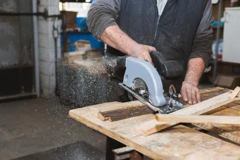 Close-up of a carpenter working circular saw. The carpenter saws wooden blocks Stock Photos