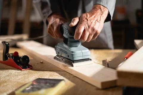 Close up of carpenter's hands using electric sander while working in carpen.. Photos