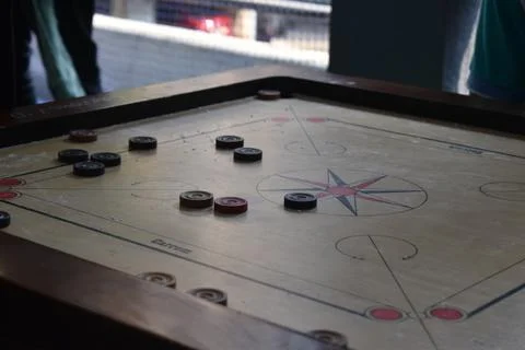 Close-Up of a Carrom Board Game in Progress with Strikers and Coins Stock Photos