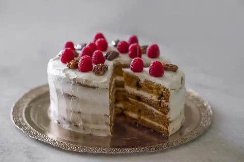 Close up carrot cake decorated with raspberry and pecan nuts. Stock Photos