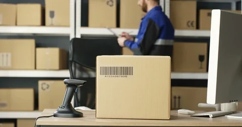Close up of carton box with bar code is on table at computer in postal office Video stock 125226212