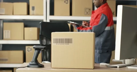 Close up of carton box with bar code is on table at computer in postal office Video stock 125226345