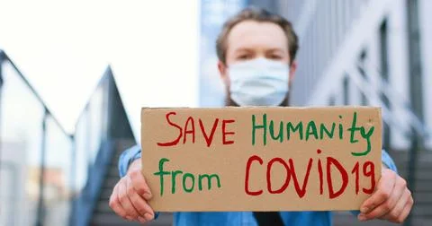 Close up of carton table with words Save Humanity from Covid 19 in hands of Stock Photos