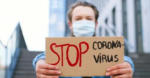 Close up of carton table with words Stop Coronavirus in hands of Caucasian young Foto stock
