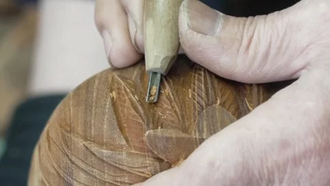 Close up of a carving chisel cutting delicate feather patterns into a wooden Stock Footage 340901399