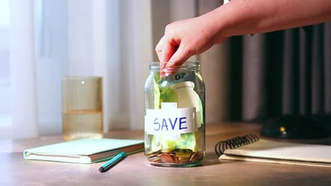 Close up of cash being added to transparent money jar. Represents traditional 库存影片 329687722
