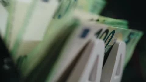 Close-up of cash counting machine processing euro banknotes, showing stacks of Stock Footage 331079641