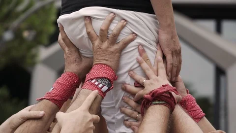 A close up of a "castellers" tower with hands holding a body. Stock Footage 102848728